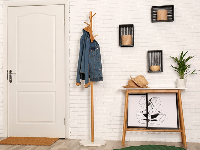 Entry area with white wall and door with coat hanger and wooden table in entry way.